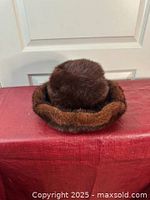 Brown women's fur hat displayed with folded brim visible, showing soft plush texture of the fur.