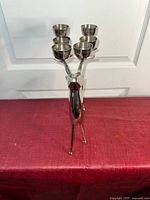 Front view of silver-colored metal deer candelabra standing on four legs, holding 6 candle cups on its antlers.