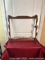 Front view of the wooden rack showing the full structure and scalloped decorative edges on top and bottom bars.