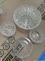 Top-down view of four glass trays showing intricate cut designs and starburst pattern on bases