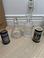 Two glass decanters and two German-style beer mugs on floor, showing overall lot contents.