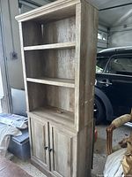 Full view of wooden bookshelf with three open shelves and cabinet base showing general condition and structure.