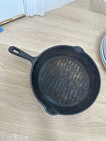 Top view of round ridged cast iron grill skillet with single handle and two pouring spouts