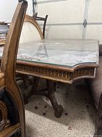 Side view of dining table showing carved details and glass top.