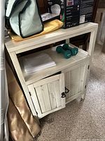 Front and side view of the farmhouse style sideboard with items on top, showing the distressed white finish and cabinet doors.