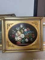 Front view of framed oil painting showing colorful flower bouquet in blue vase with gold decorative frame and corner accents.