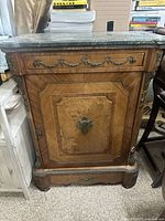 Front view of the antique console showing the wooden body with marble top and metal decorative accents.