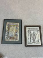 Front view of two framed Judaica art pieces featuring Hebrew texts and menorah designs