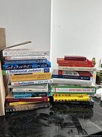 Photo of a stacked collection of various paperbacks and hardcover books on different topics and genres.