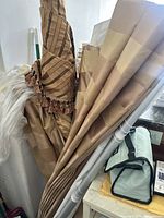 Multiple folded curtain fabric pieces, including a beige striped fabric with fringe.