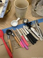 Le Creuset utensil holder and various knives and kitchen utensils laid out on floor