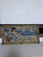 Full front view of the needlepoint tapestry showing the reclining nude female figure with three white doves against a cloudy sky background in a gilded frame.