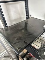 Photo of Samsung 32-inch TV placed face up on a metal shelf, showing flat screen surface with reflections and no remote control visible.