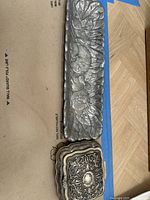 Top view of rectangular bunny tray with embossed rabbits and leaves alongside the closed ornate jewelry box