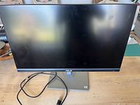 Front view of Asus ProArt PA278CV monitor powered off, showing screen and stand with power cable.