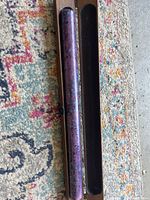 Ceramic flute closed in its black protective case laid on a colorful carpet.