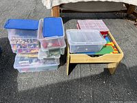 Overall view of multiple clear plastic bins stacked and LEGO table next to them.