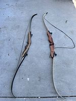 Photo of two recurve bows side by side on ground showing full length and shape.