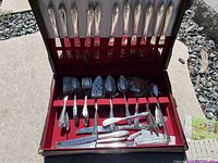 Full view of the flatware set showing multiple types of cutlery in red velvet-lined case with lid open.
