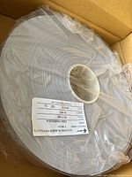 Close-up photo of a roll of Fujipoly thermal interface material wound on a white core with a label showing product details.