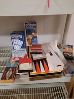 Photo showing an assortment of boxed games including Dominoes, Deluxe Boggle, backgammon, cards, and other board games.