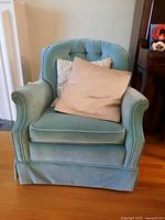 Front view of blue upholstered armchair with beige and white patterned cushions on seat