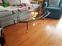 Photo of the glass top coffee table showing the metal base with spiral legs and curved supports under clear glass top.