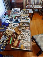 Full table view showing assortment of jewelry including necklaces, bracelets, watches, key chains, and jewelry boxes arranged on the table.