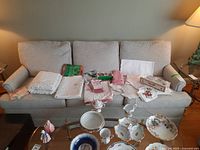 Front view of light gray upholstered couch showcasing three seat cushions, three back cushions, and rolled arms on each side.