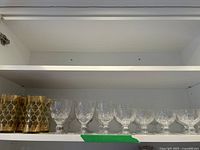 Shelf view showing the 4 gold overlay crystal glasses on the left and 10 cut crystal stemware glasses arranged on the right.