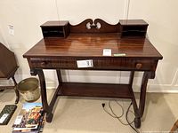 Front view of wooden writing desk showing single drawer and two cubbyhole compartments on tabletop.