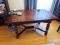 Front view of closed table showing tabletop surface, apron and carved turned legs