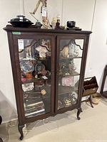 Front view of wood display cabinet with glass doors showing contents inside and overall finish.