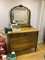 Front view of vintage oak dresser with attached mirror and objects on top (not included). Shows the grain and warm finish of oak wood and metal drawer pulls.