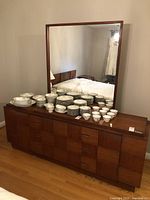 Front view of dresser with mirror and dishware on top