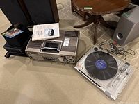 Wide view of the Sears Betavision VCR, Sony turntable with record on platter, CD cases, and cleaning accessories in a room.