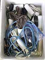 Box filled with an assortment of extension cords in various colors and types.