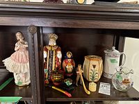 Full view of the figurines, nesting dolls, trinket boxes, ceramic pitchers, and glass vase arranged on a wooden surface