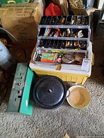 Overview of all items: tackle box with lures on top of yellow Coleman cooler, green metal case, enamel pot and bowl