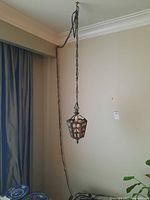 Full view of hanging lamp showing chain and lamp body hanging from ceiling.