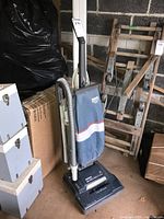 Full view of Hoover Elite II upright vacuum cleaner showing blue fabric dust bag, gray flexible hose, and control handle.