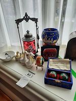 Full view of all items: four ceramic duck figurines, glass candle bowl, hand painted glass egg on stand, decorative red and black candle holder, and blue box containing health balls.