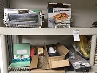 Shelf showing the full Proctor-Silex toaster oven, expandable trivet box, set of ramekins, candle holders, and mandoline slicer