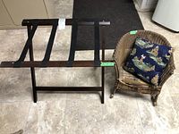 Photo showing the wooden luggage rack next to the small wicker rocking chair with cushion.