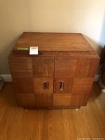 Front view of teak veneer Mid-Century Modern night stand, showing two doors and layered top with wear.