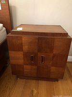 Front view showing the checkered teak veneer wood pattern with two doors and wooden handles.