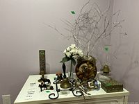 Photo showing the entire lot on a white surface, including the oil lamp, faux florals, incense burner, easel, figurines, metal box and decorative branches.