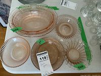 Overhead view of six pink glass serving ware pieces including bowls and plates on a white surface