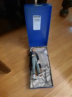 Blue presentation box open on hardwood floor, showing satin lining and figure inside