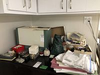 Sewing machine and sewing supplies spread on a black surface, includes hard case, fabric, and notions